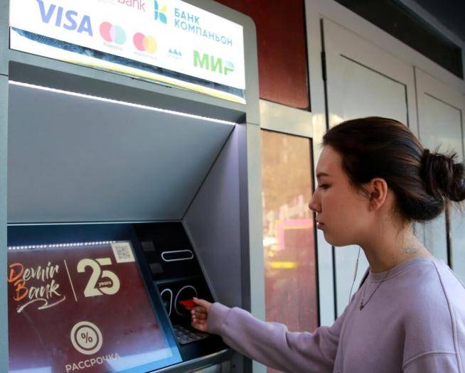 Девушка с картой Мир от банка Сбербанк у банкомата в Бишкеке