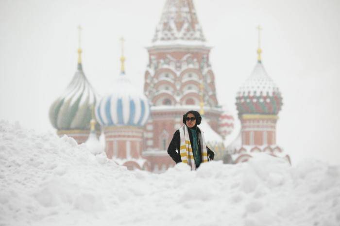 Прохожие на Красной площади во время снегопада в Москве