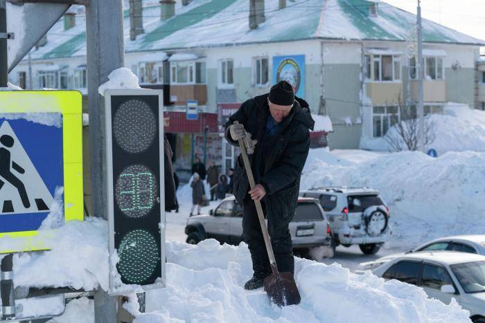 Мужчина убирает снег в Петропавловске-Камчатском