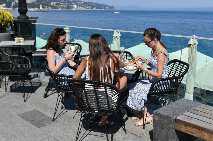 Отдыхающие в кафе на берегу Черного моря в Ялте