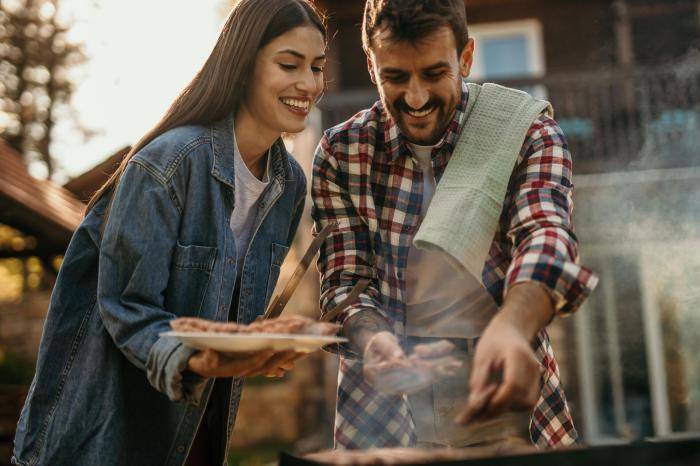 Молодые люди готовят мясо на гриле