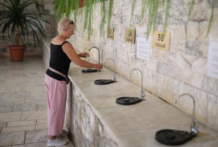 Женщина наливает минеральную воду в питьевой галерее на курорте Горячий ключ в Краснодарском крае