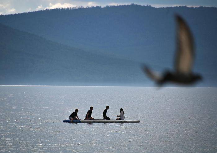 Люди плывут на сап-борде по озеру Тургояк в Челябинской области