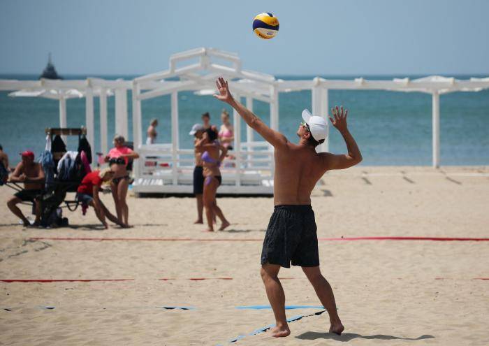 Молодой человек играет в волейбол на пляже в Анапе