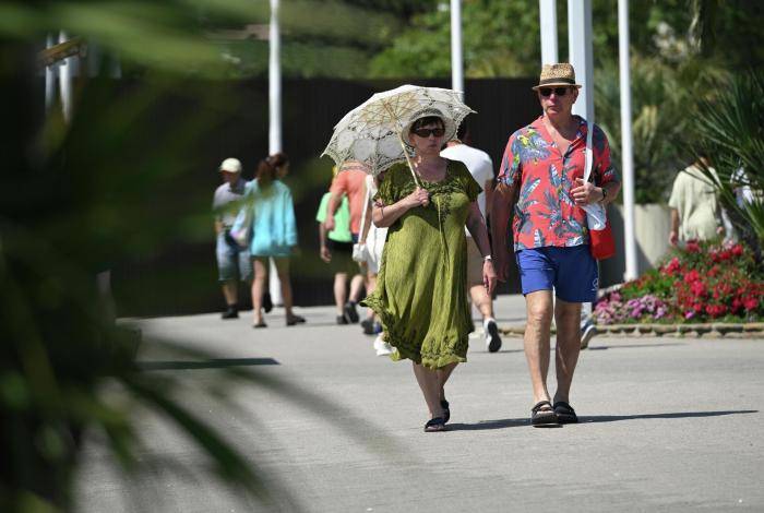 Люди гуляют по набережной у пляжа