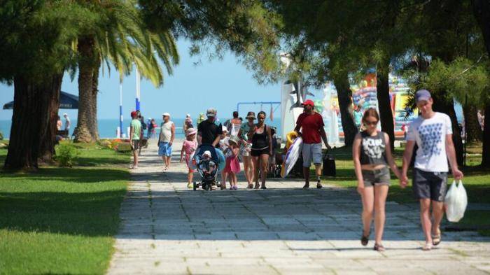 Отдыхающие идут с пляжа в Пицунде