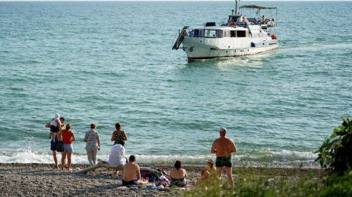Отдыхающие на берегу Черного моря в городе Новый Афон в Абхазии
