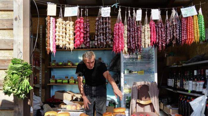 Продавец чурчхелы за прилавком на рынке в городе Новый Афон в Абхазии