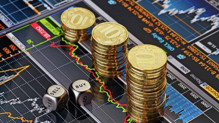 Стопки десятирублевых монет на экране с биржевыми графиками