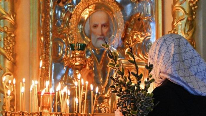 Верующая с букетом вербы в храме Успения Божией Матери в Успенском православном мужском монастыре в Красноярске
