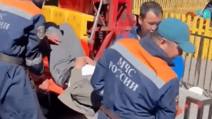 Сотрудники МЧС эвакуируют одного из юношей, зажатых в подвесном кресле на аттракционе в Туве