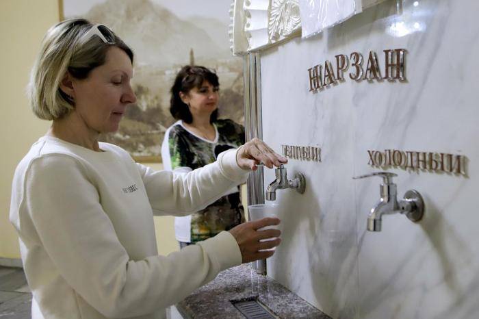 Пациентки наливают в стакан минеральную воду нарзан в бювете санатория имени Георгия Димитрова в Кисловодске
