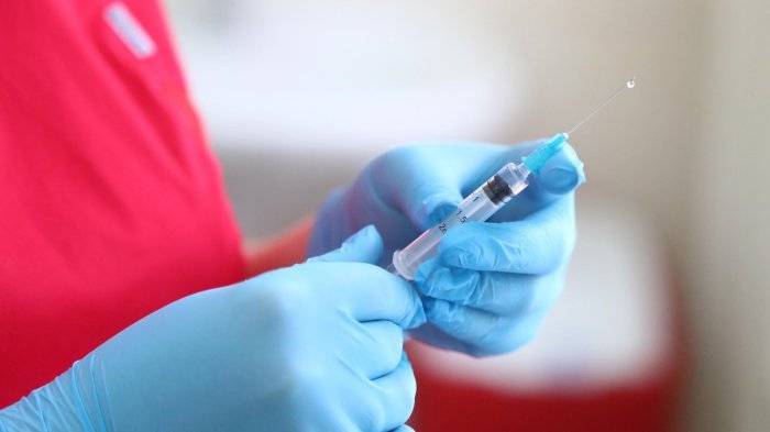 Медицинский работник держит шприц
